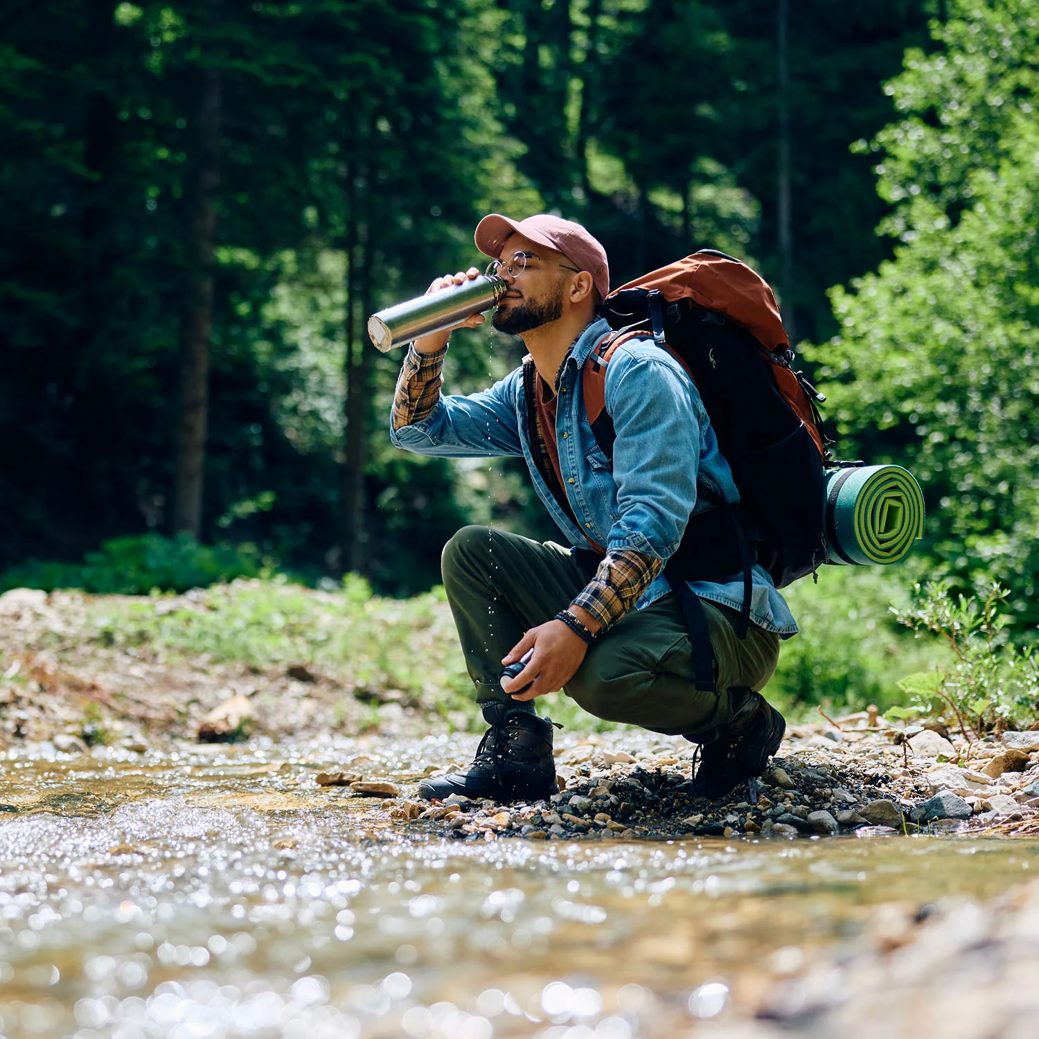 Ein Mann der auf seiner Wanderung Wasser trinkt.