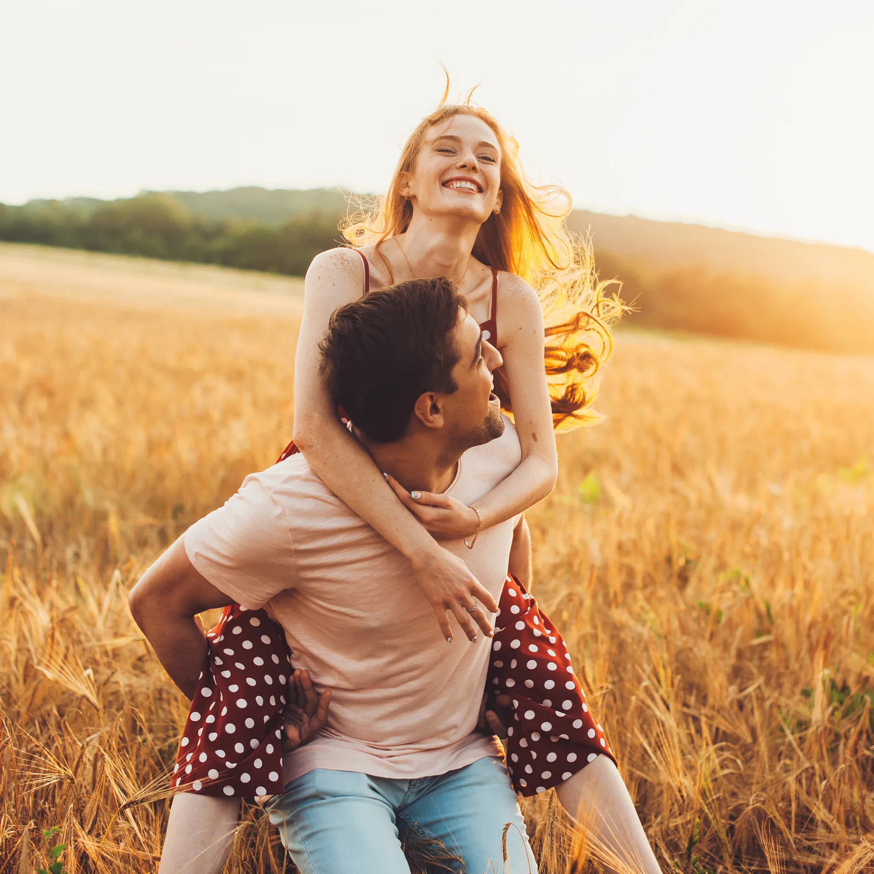 Momentaufnahme eines Mannes, der eine Frau auf dem Rücken hat und beide glücklich zusammen lachen.